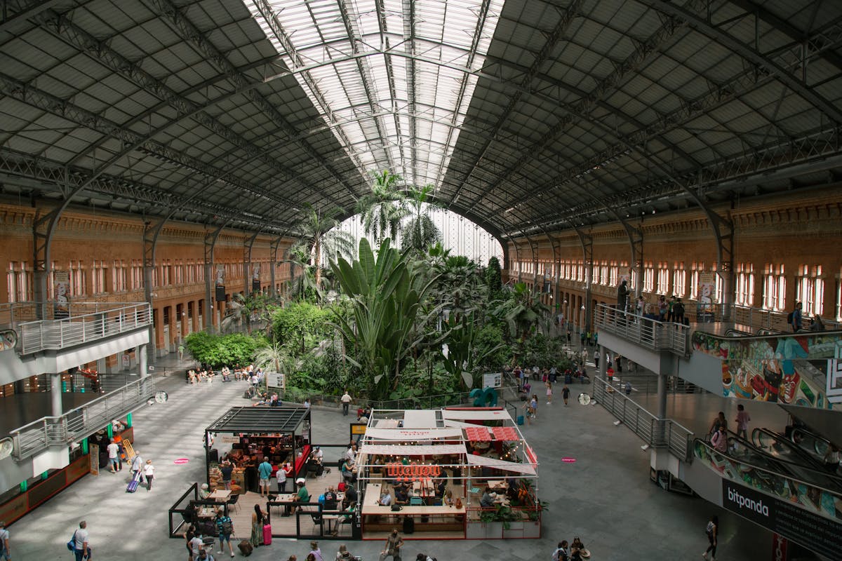 Inside Madrid Atocha station with lush tropical garden and visitors
