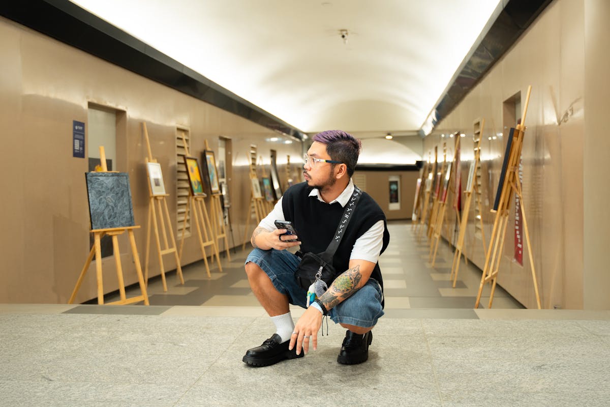 A young man examines art pieces in an indoor gallery with bright lighting