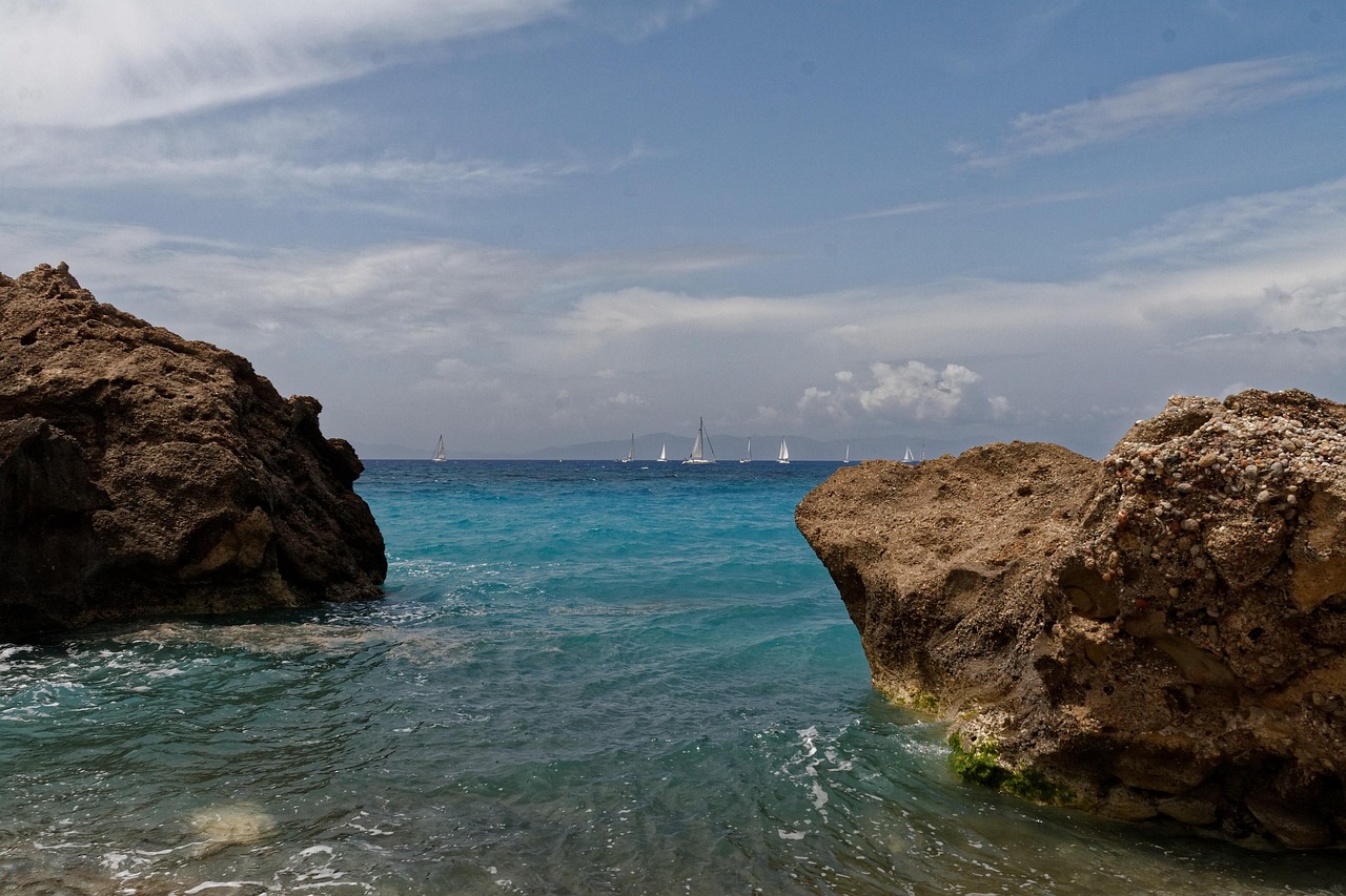 White sailboat near rocky coastline in Rhodes Greece