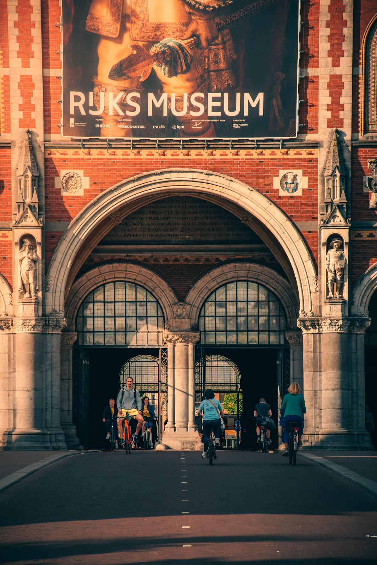 Cyclists passing through the iconic arched passage beneath the Rijksmuseum