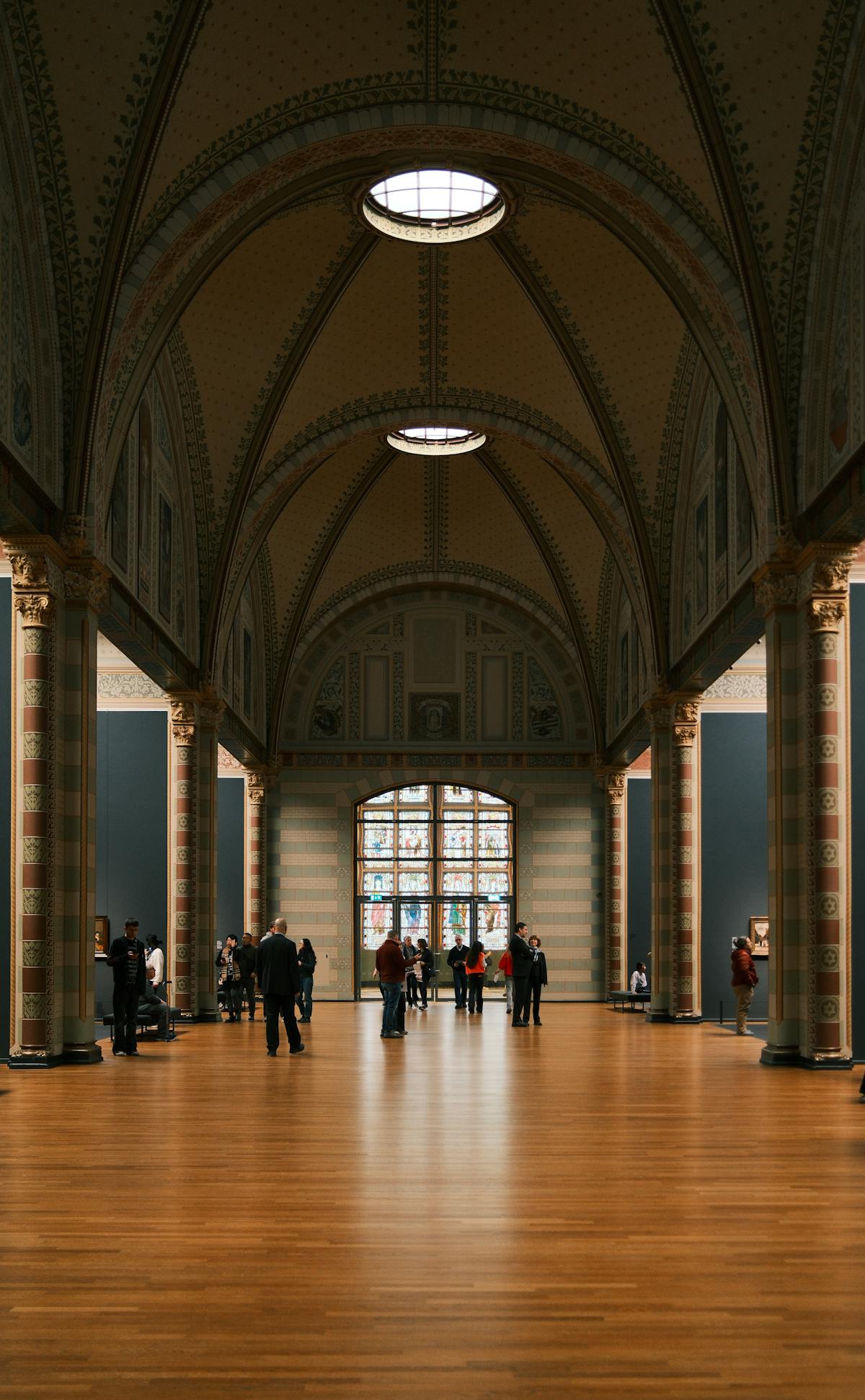 Long elegant corridor inside the Rijksmuseum with arched ceilings and visitors
