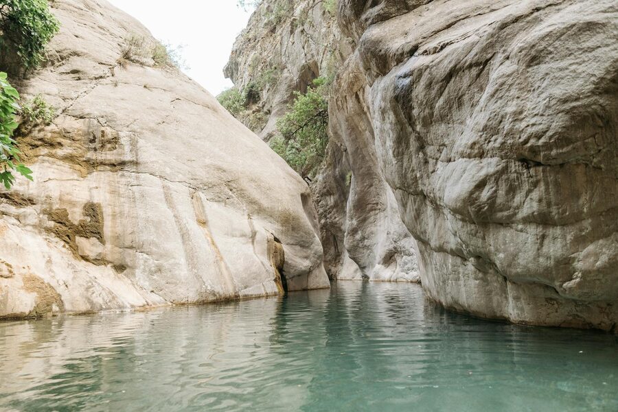 Rocky canyon walls with a calm clear stream reflecting the rock formations