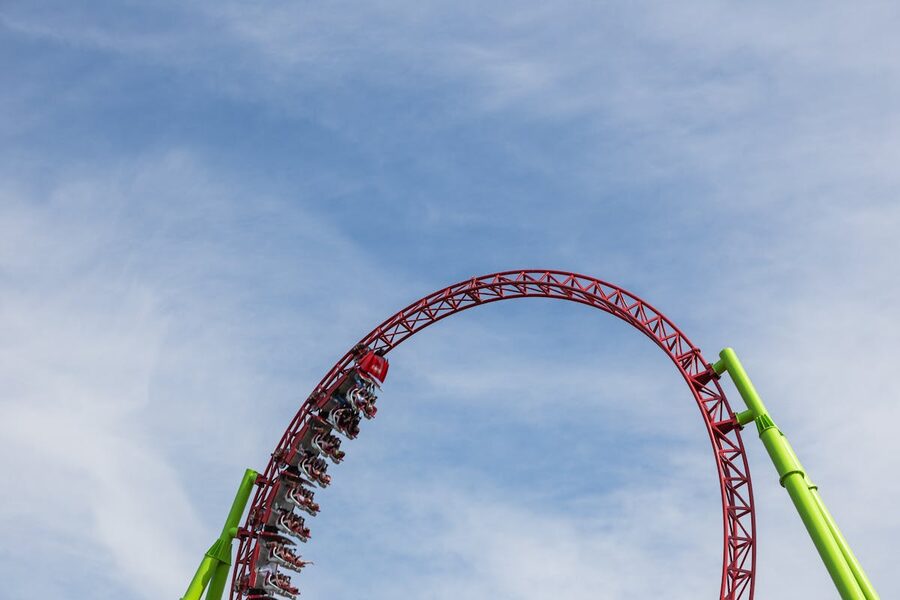 Roller coaster completing a loop against a clear blue sky at a theme park