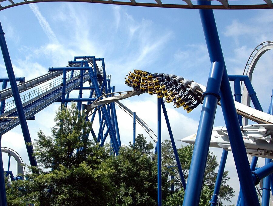 Roller coaster performing a large loop with natural surroundings and blue sky