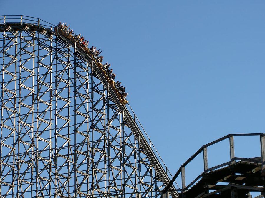 Roller coaster cars climbing to the steep peak of a ride at an amusement park