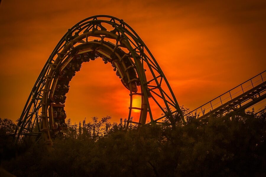 Roller coaster silhouetted against a dramatic sunset sky at a theme park