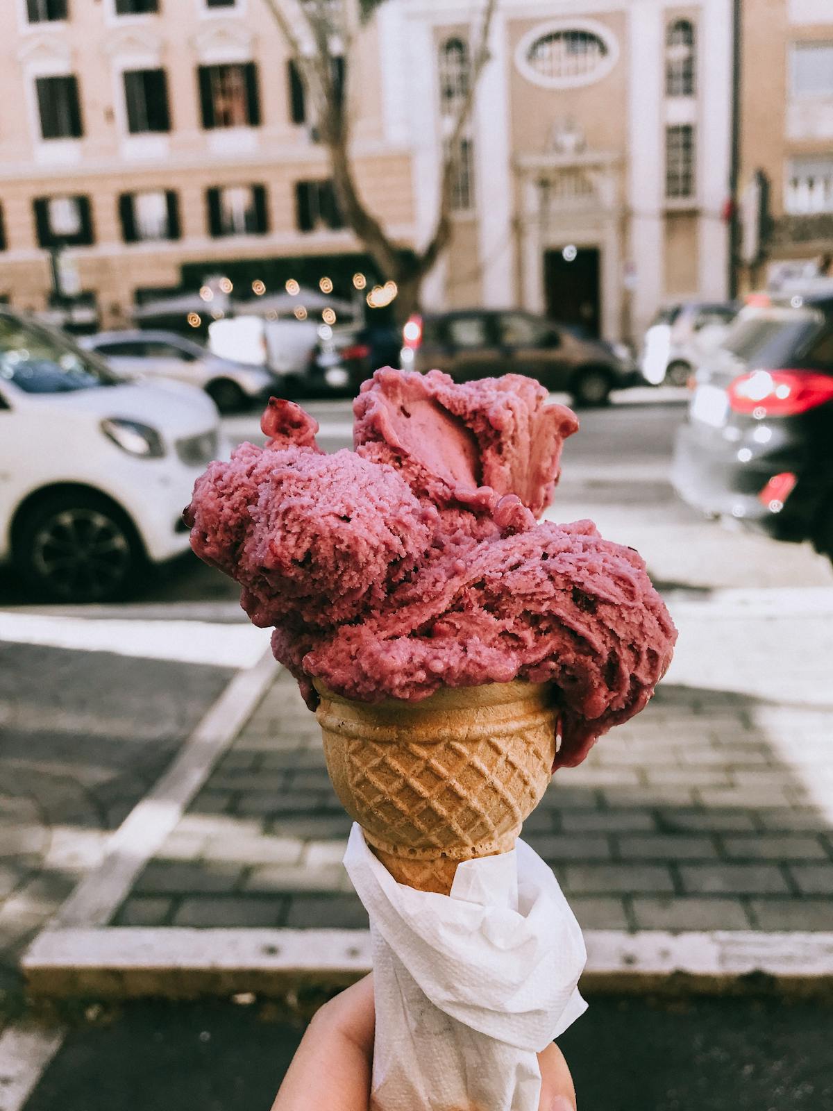 Colorful gelato cone held outdoors in Rome on a sunny day