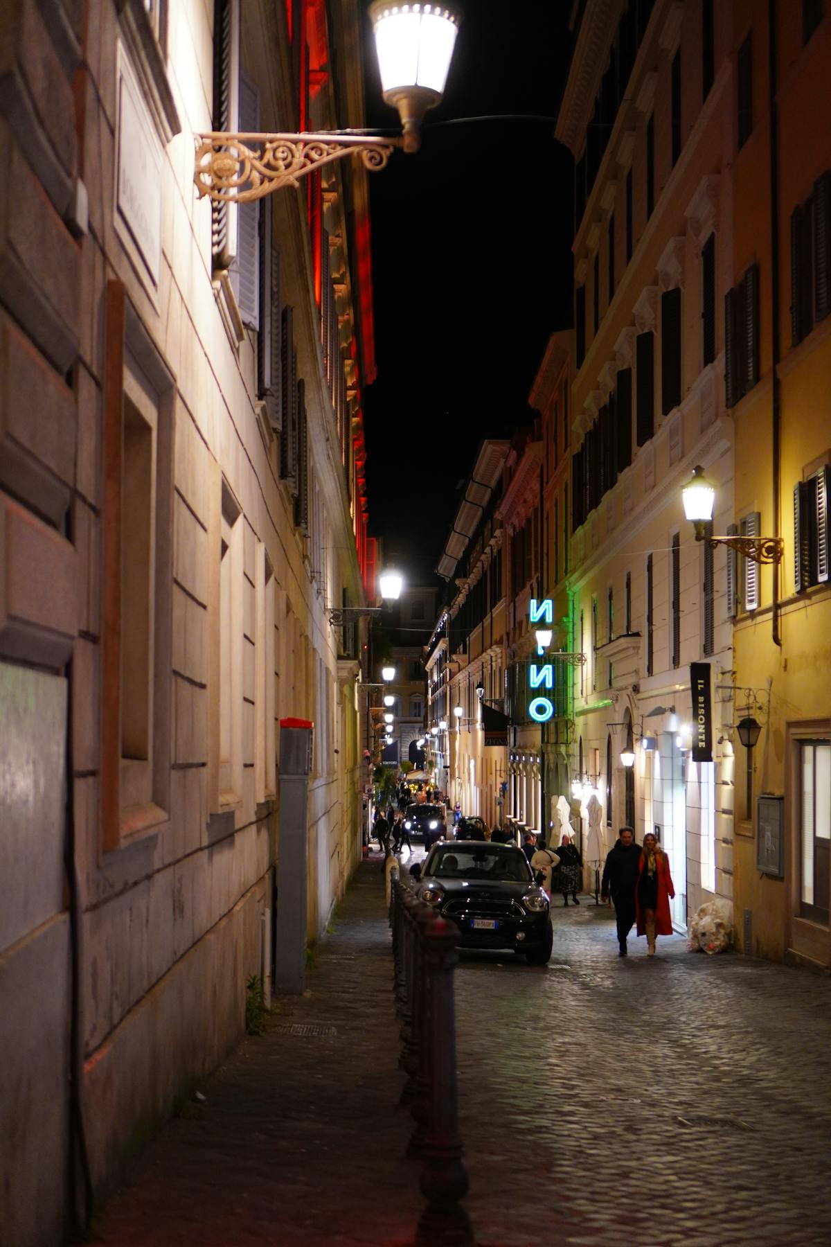 Cobblestone alley in Rome illuminated by warm street lamps at night