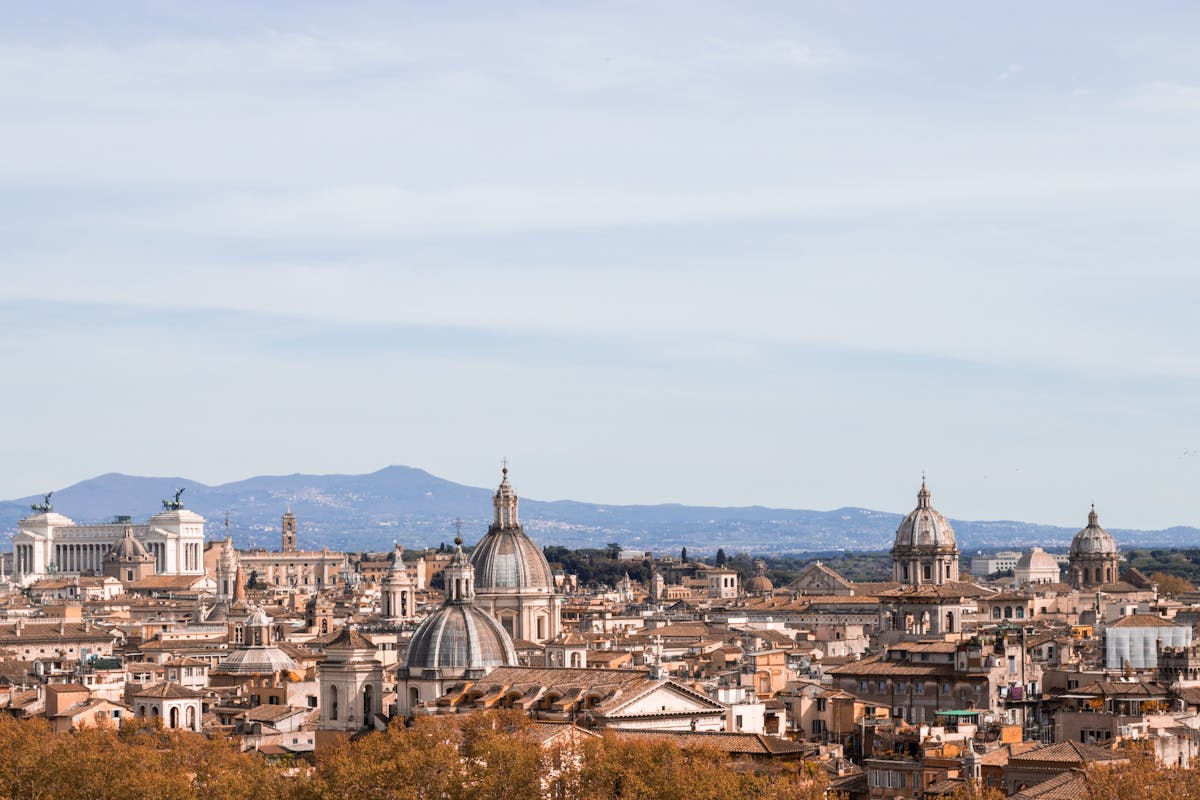 Sweeping panoramic view of Rome rooftops and historic buildings under a clear sky
