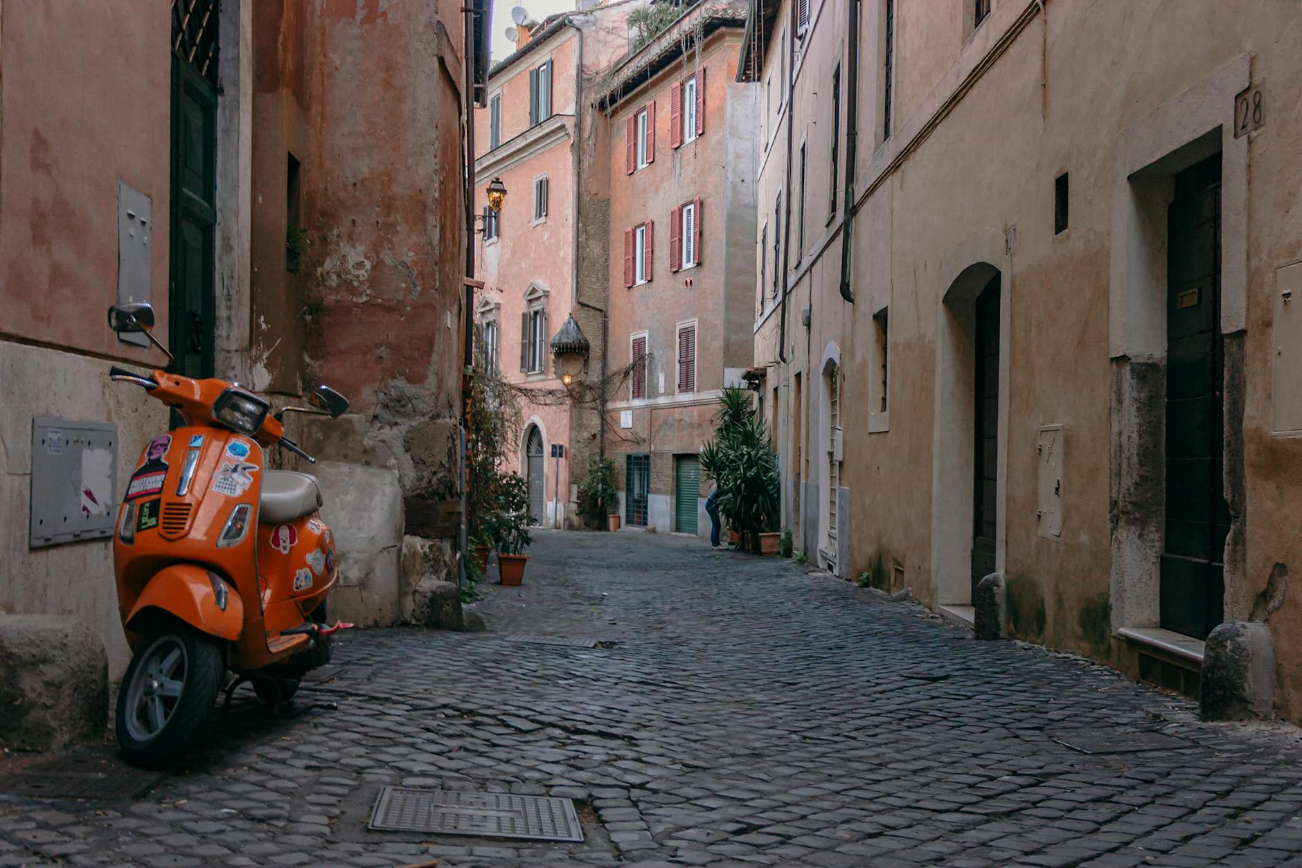 Orange scooter parked on a cobblestone street in Trastevere Rome