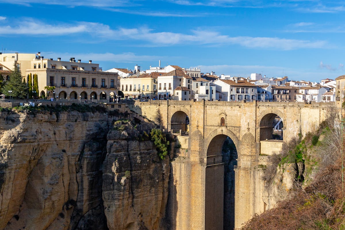 The iconic Puente Nuevo bridge in Ronda Spain on a clear sunny day stretching across the gorge with blue sky above