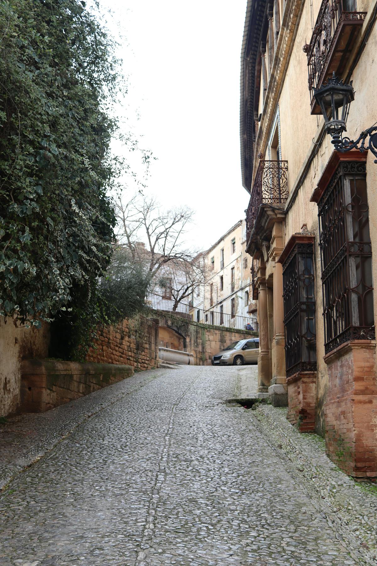 Picturesque cobbled street in Ronda with historic stone buildings and Andalusian architecture