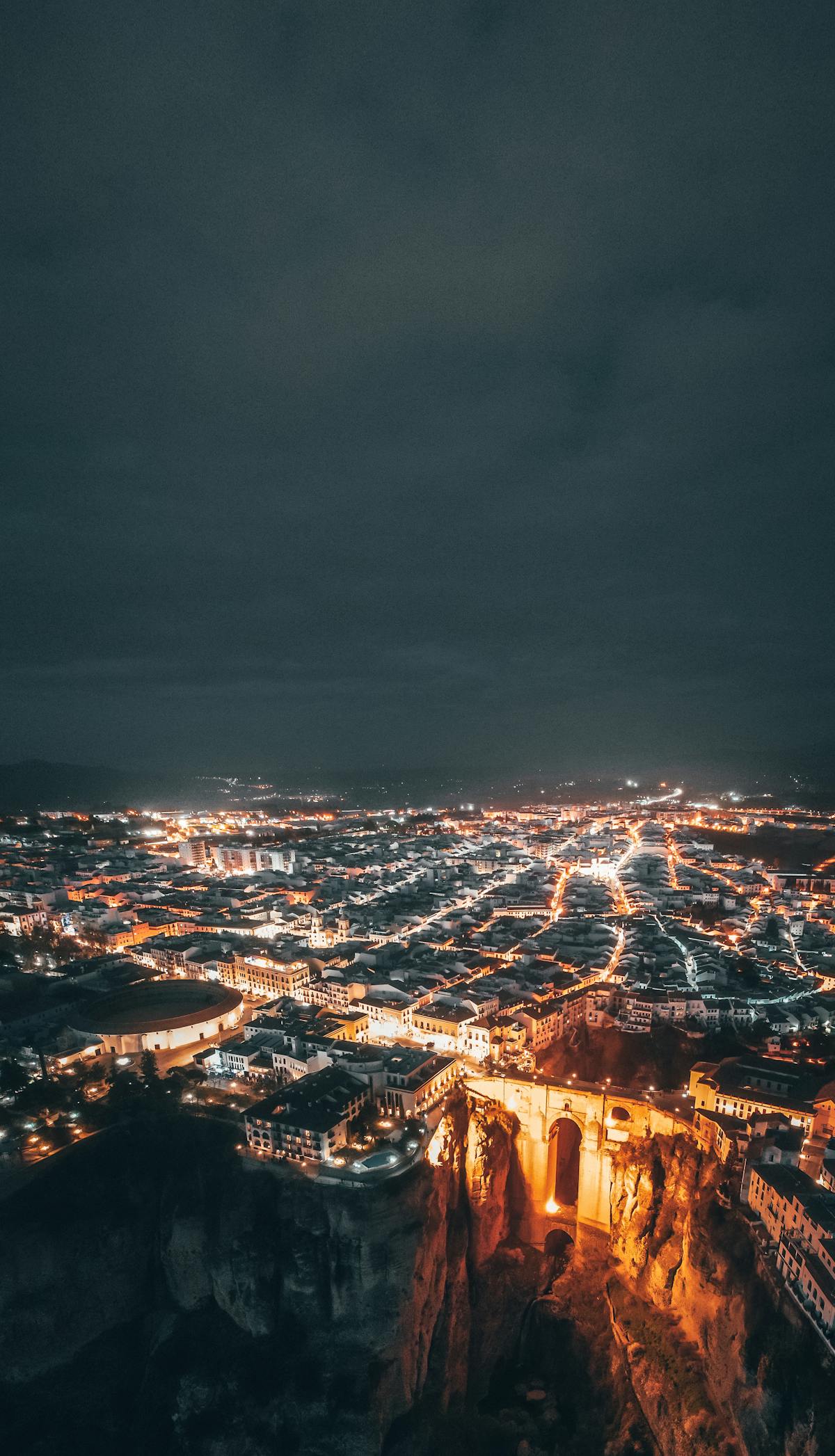 Ronda Spain illuminated at night with the bridge and cliff-top buildings glowing against the dark sky