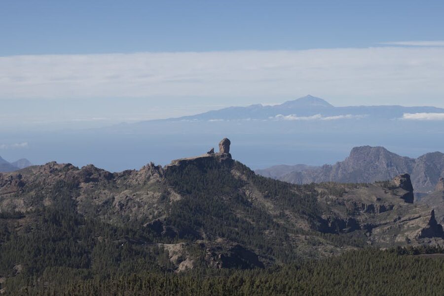 Panoramic view of Roque Nublo rock formation with Mount Teide visible across the sea in Tenerife