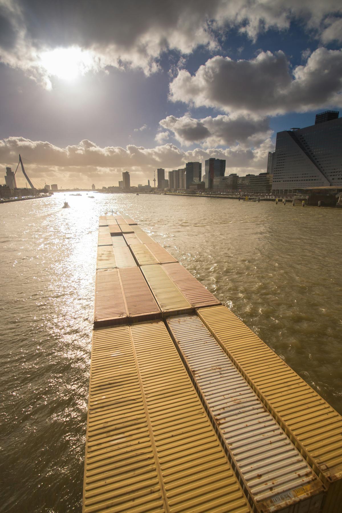 Container ship navigating past the Rotterdam skyline on the Maas River