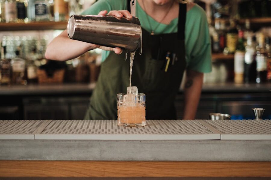 Bartender pours cocktail in stylish bar setting