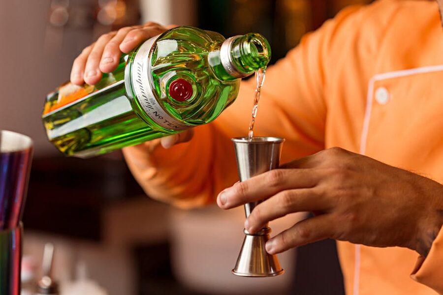 Bartender pouring gin into jigger close-up