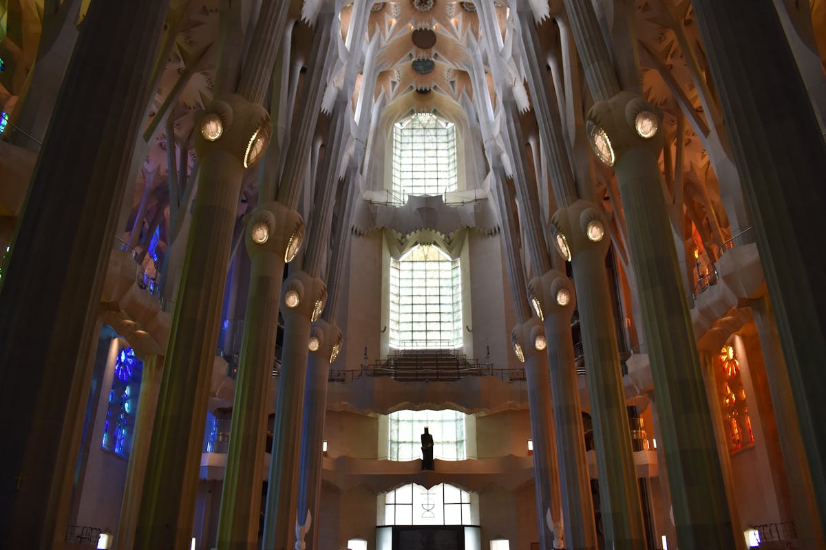 Interior of Sagrada Familia showing the full height of stained glass windows casting warm light across the nave