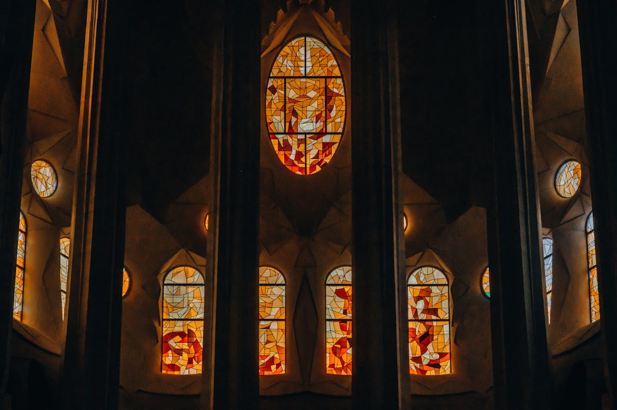 Stained glass windows inside Sagrada Familia casting colourful light across stone walls