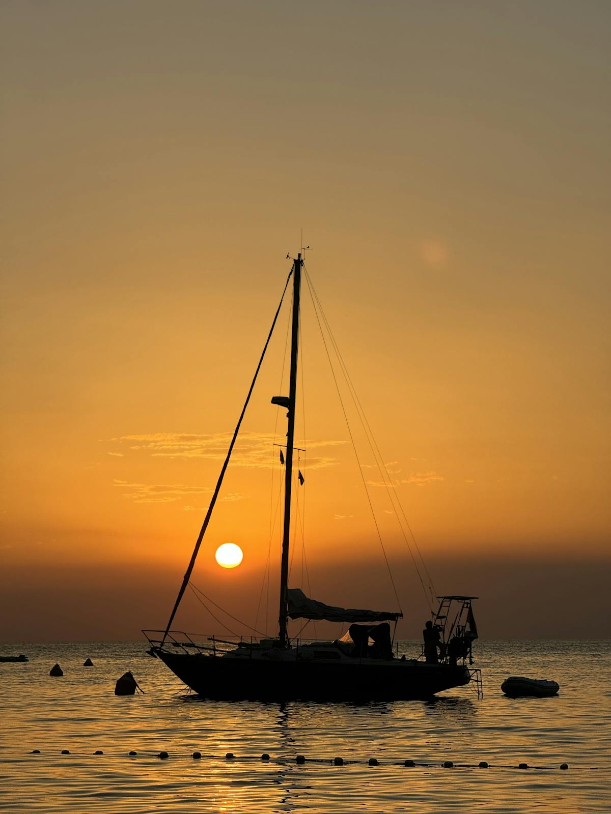 Sailboat silhouette against orange sunset on the Mediterranean Sea