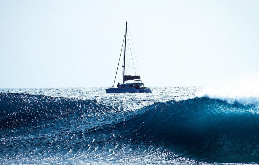Sailboat cutting through waves at sunset