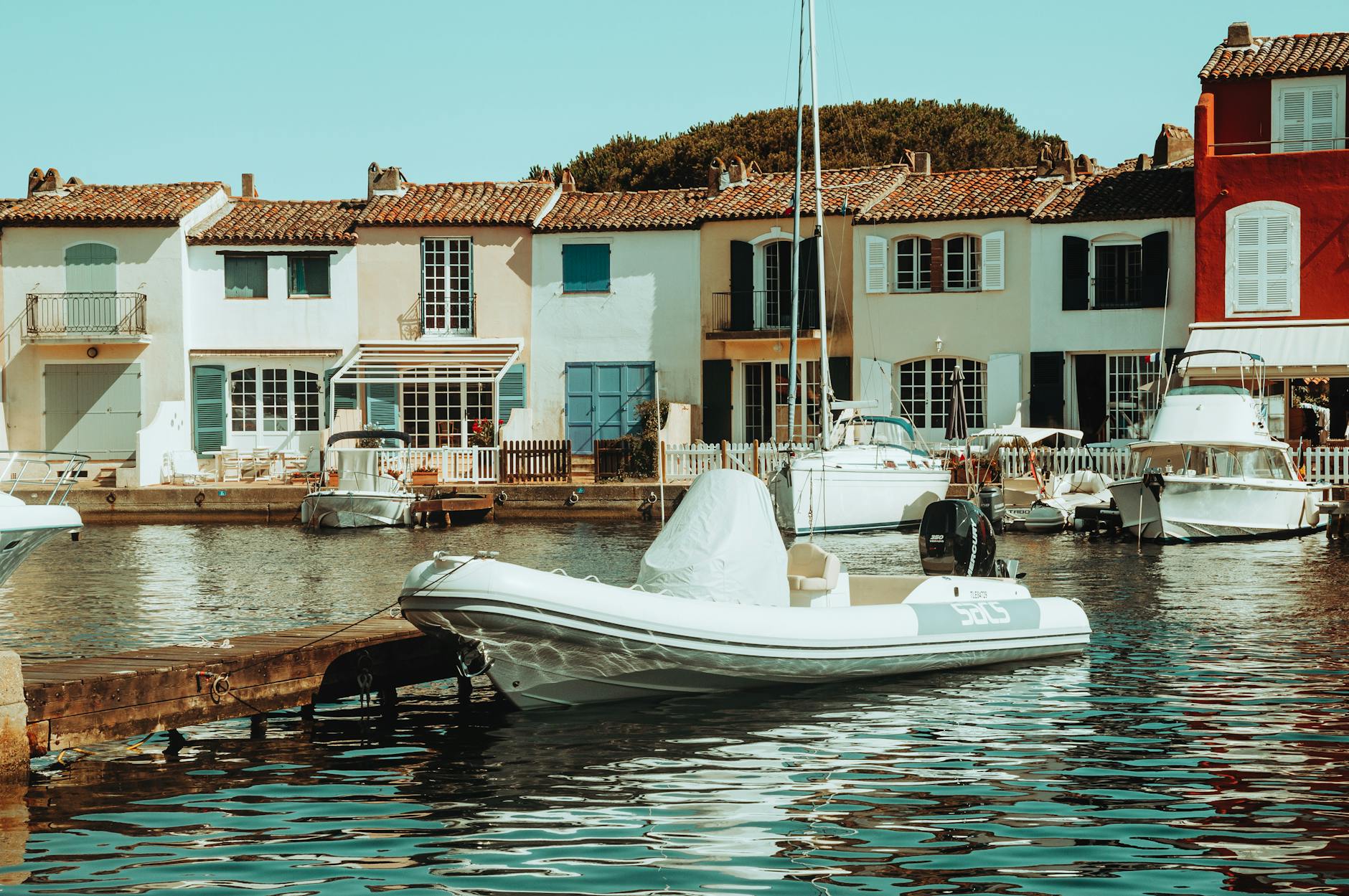 Colourful boats along a narrow canal in Saint-Tropez with stone buildings