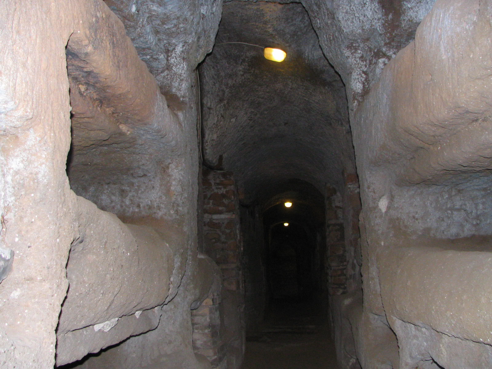 Narrow stone passage inside the Catacombs of San Callisto showing burial niches
