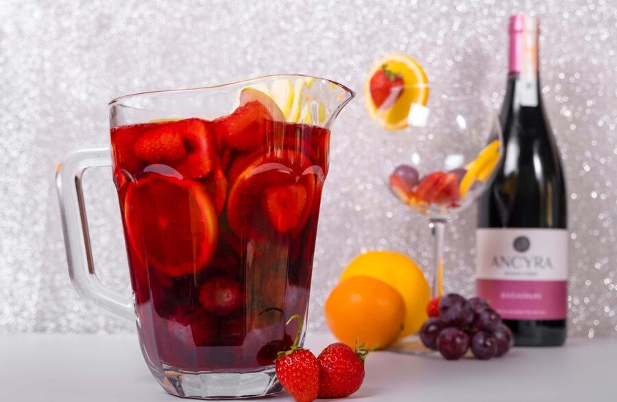 A pitcher of sangria next to a wine bottle with fresh fruits