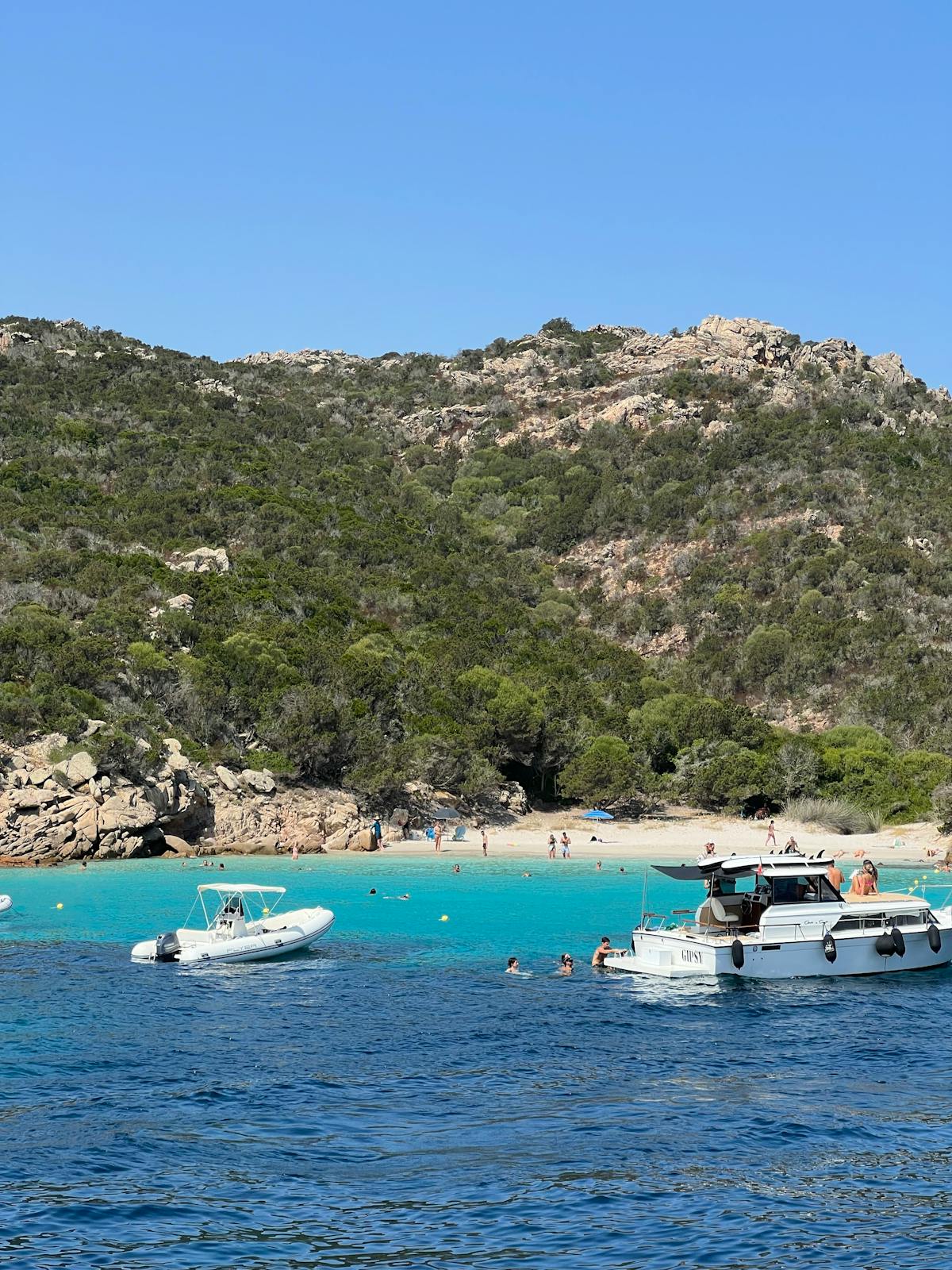 Boats anchored near a serene Sardinian beach with crystal clear turquoise waters
