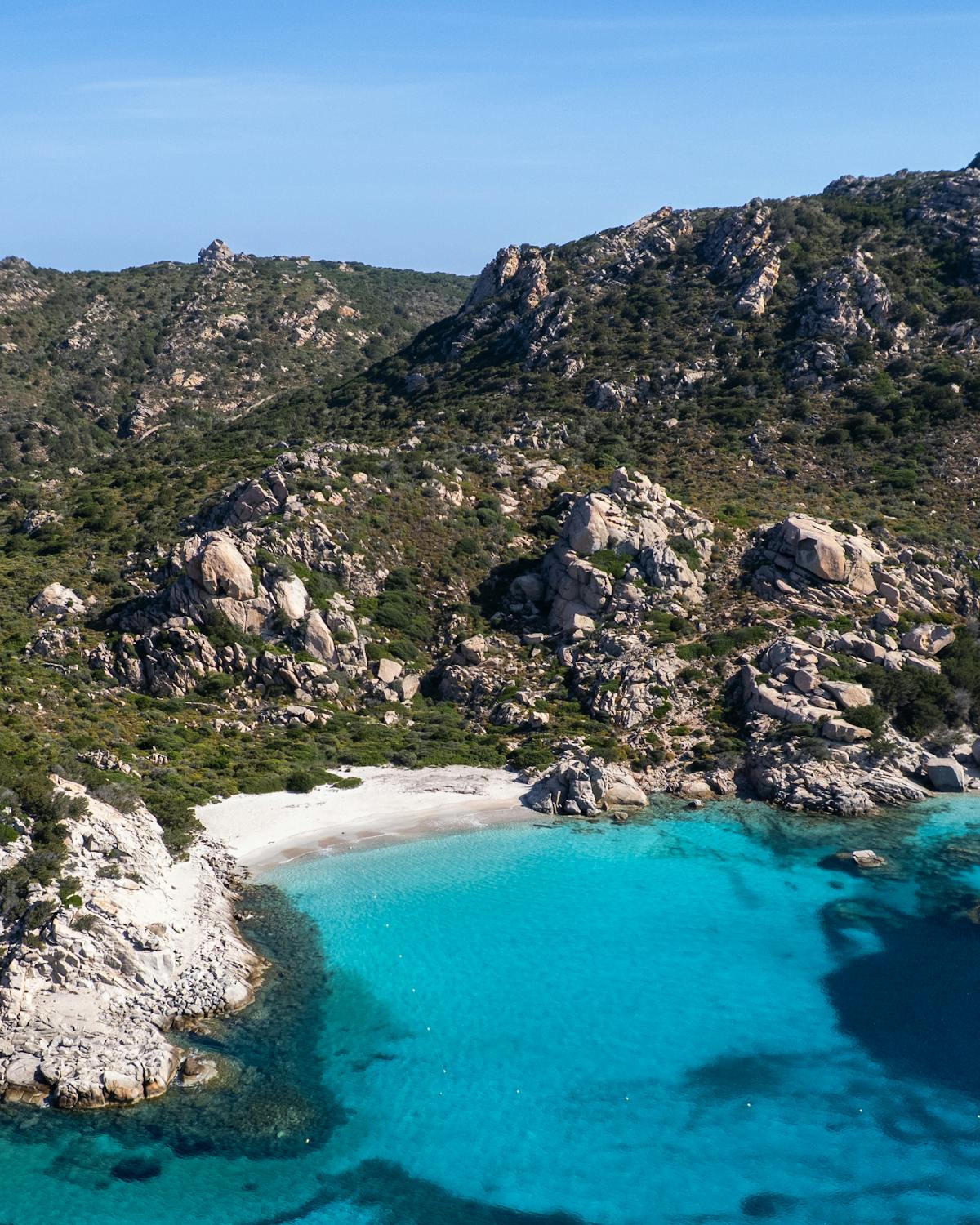 A secluded Sardinian beach with turquoise waters surrounded by rocky cliffs