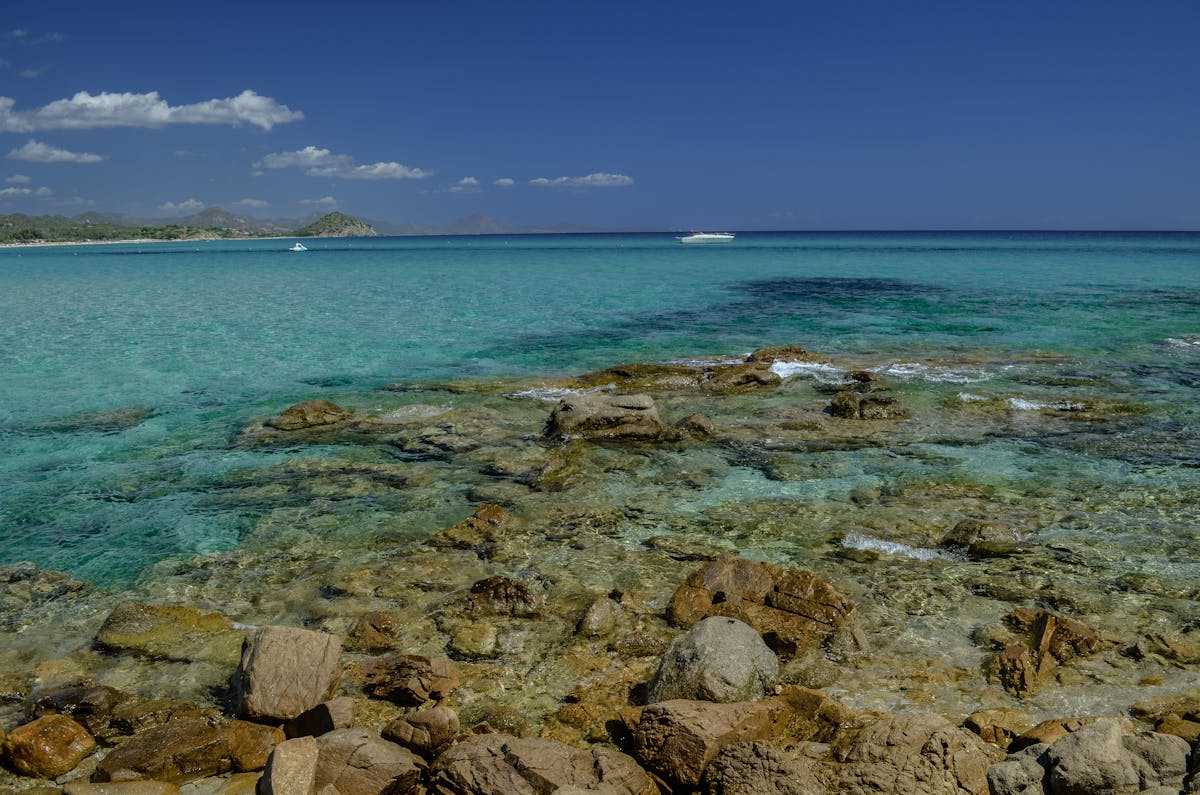 Clear turquoise waters and rocky coastline of Sardinia under blue skies
