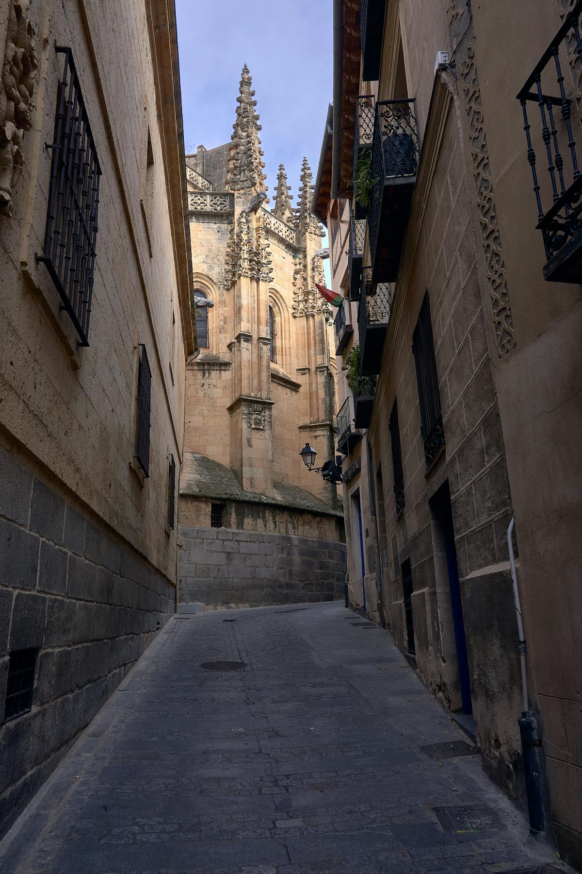 A quiet cobblestone street in Segovia with traditional stone buildings and iron balconies