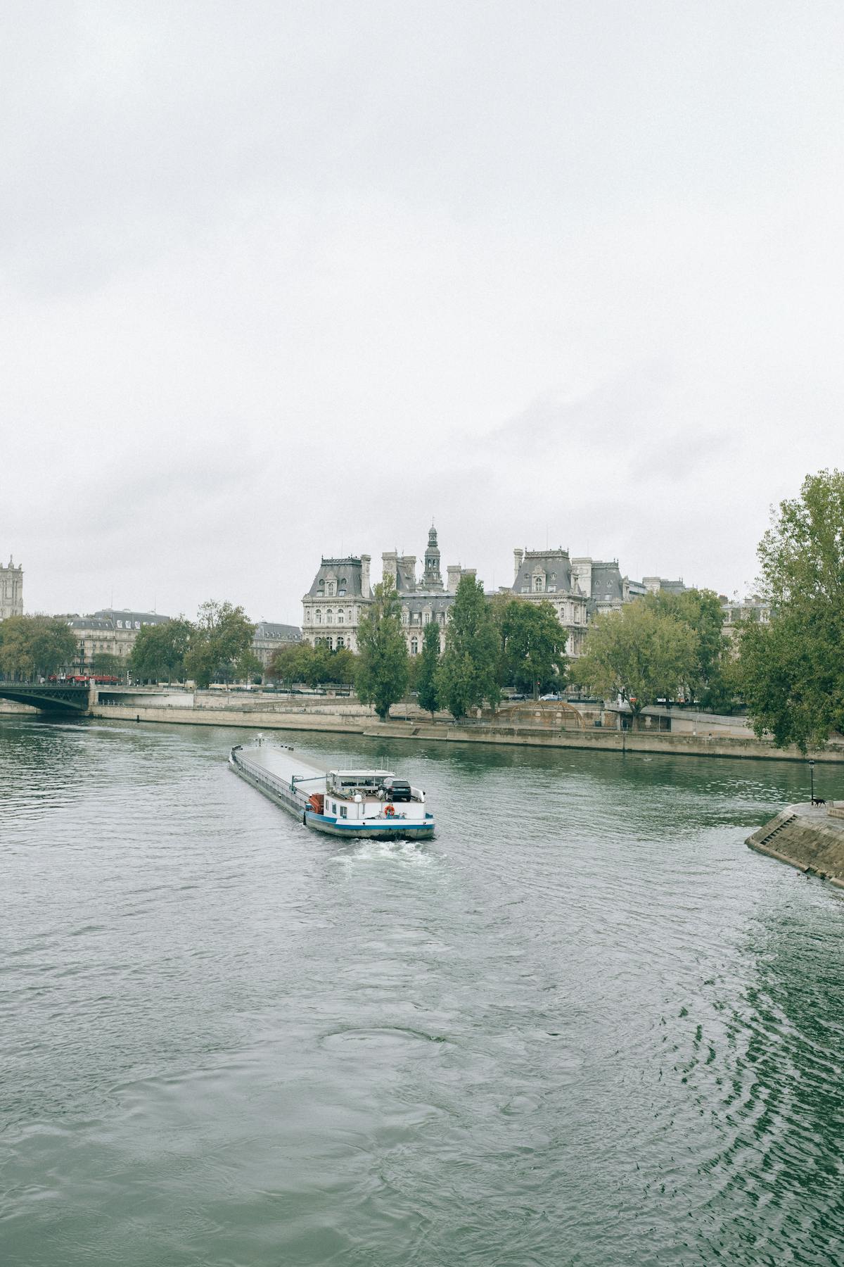 A boat cruising down the Seine River with classic Parisian buildings on each side