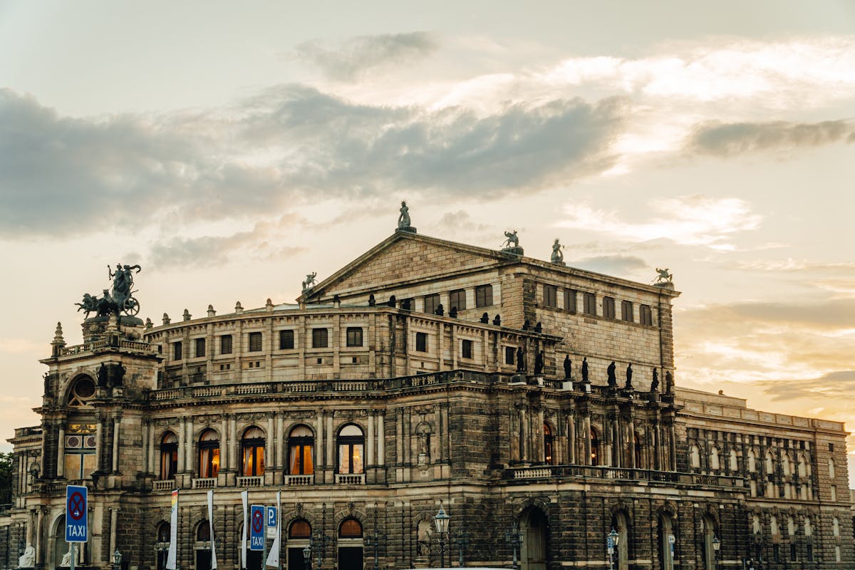 The Semperoper opera house in Dresden bathed in warm sunset light with the Theaterplatz in the foreground