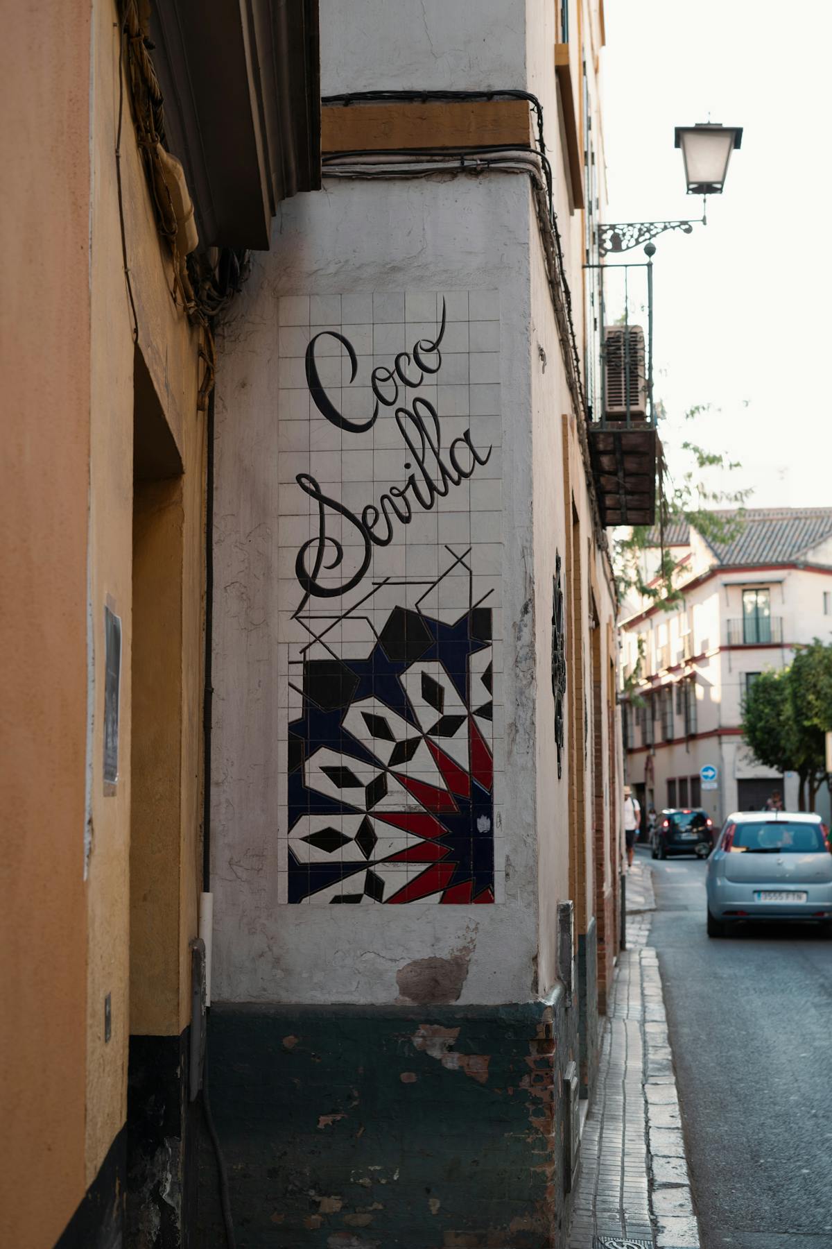 Decorative ceramic street art and hand-painted sign on a corner in Seville