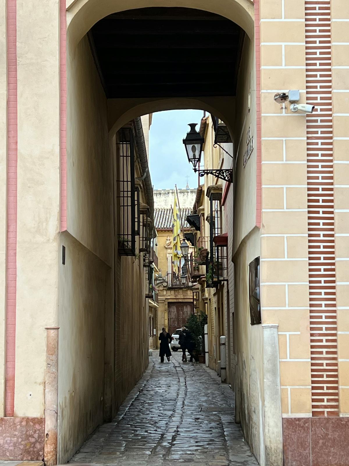 Cobblestone street in Sevilles old town with arches and historic whitewashed buildings