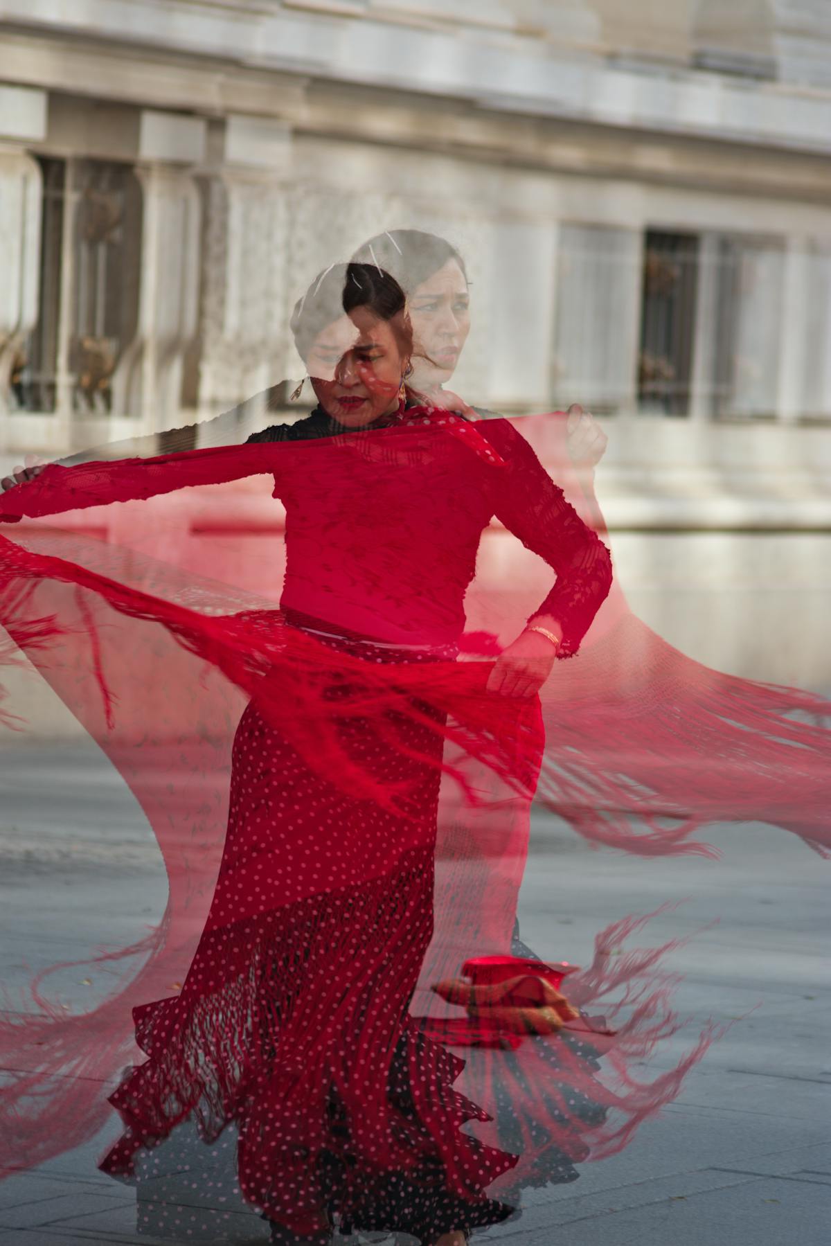Flamenco dancer in red dress performing in a classic Seville architecture setting