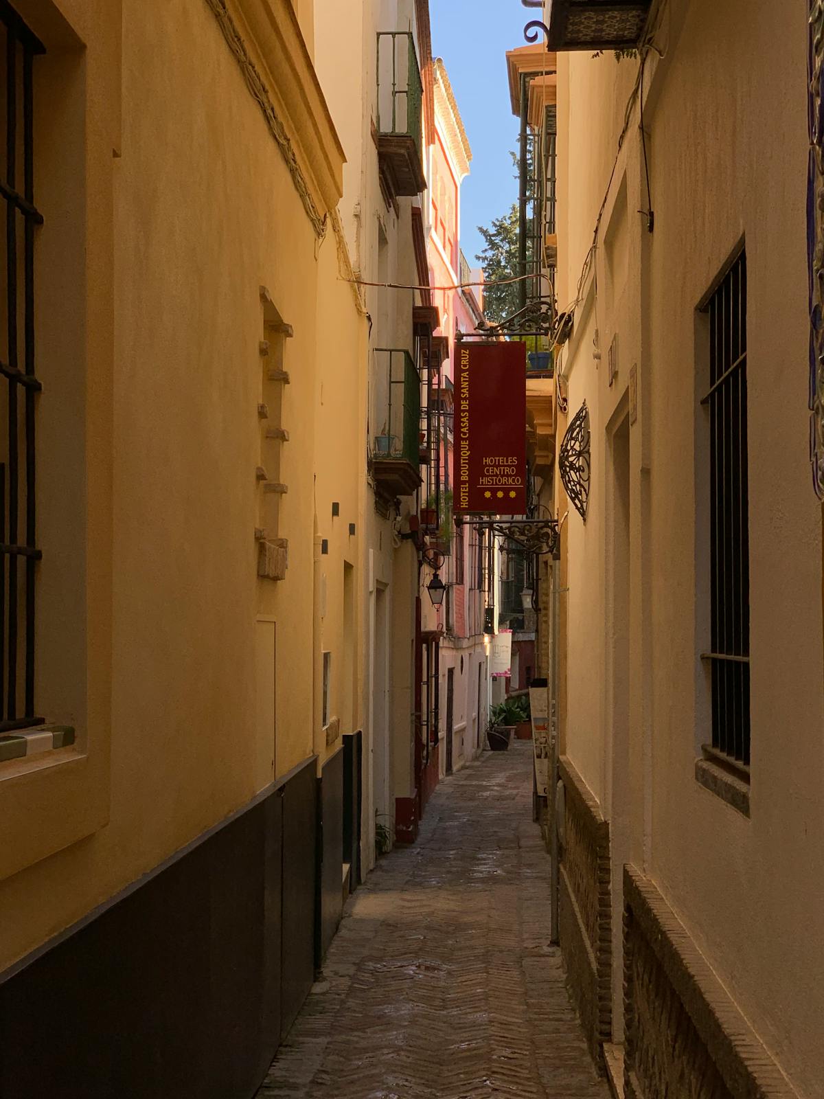 Narrow alleyway in Seville Santa Cruz neighborhood with traditional Andalusian architecture