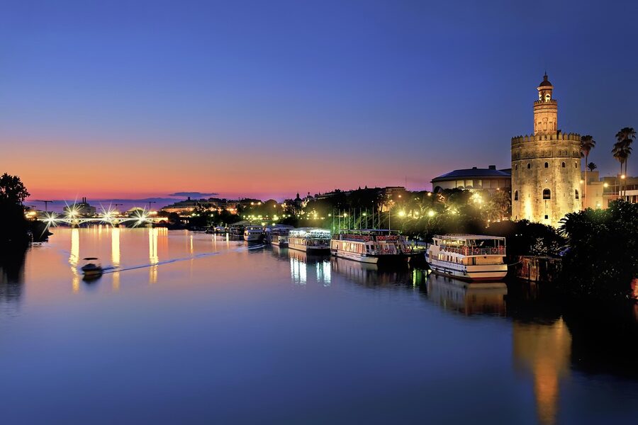 Seville riverfront at night with city lights reflecting on the Guadalquivir