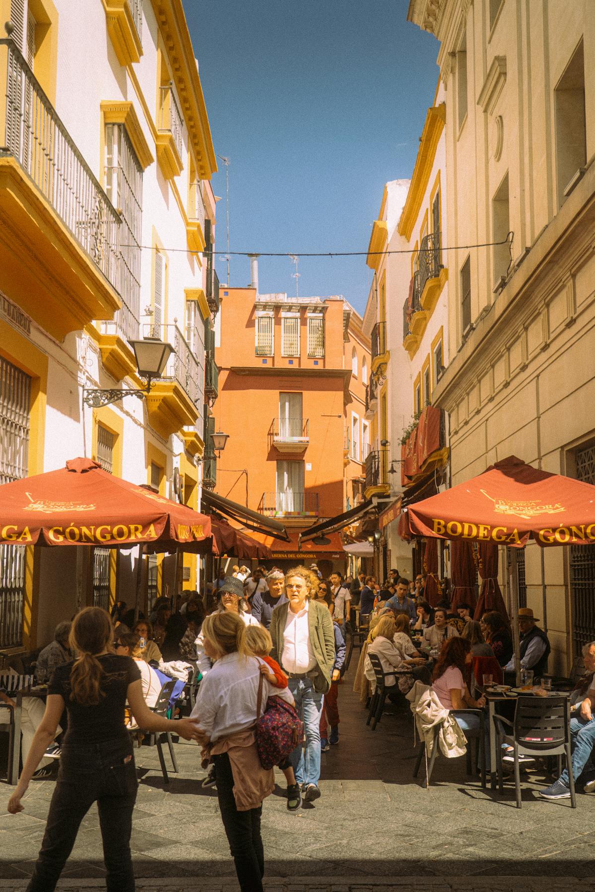 People enjoying a sunny day at street cafes in Seville surrounded by historic architecture