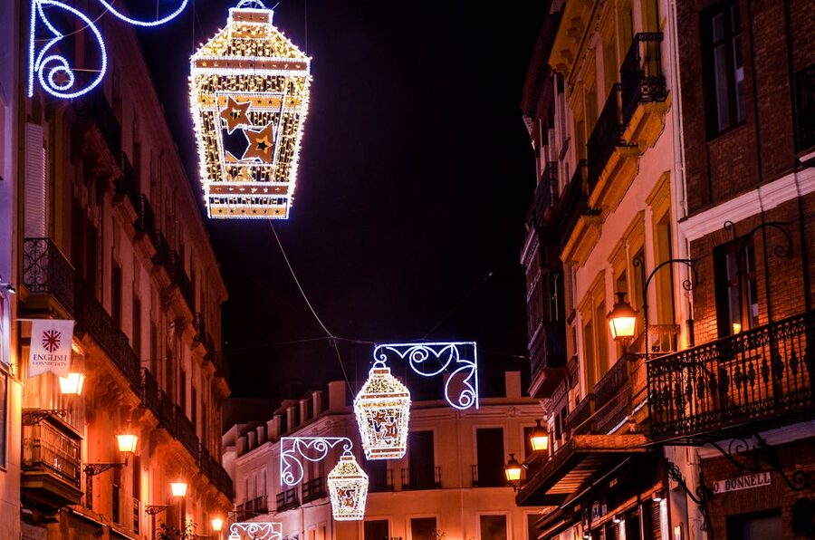 Historic narrow street in Seville lit by hanging lanterns at dusk