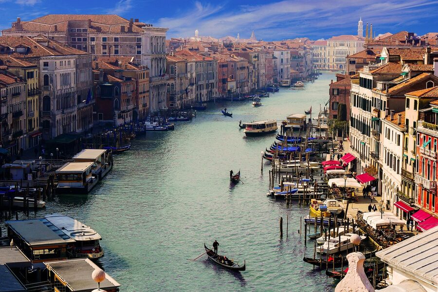 Gondolier steering gondola on the Grand Canal in Venice with city in background