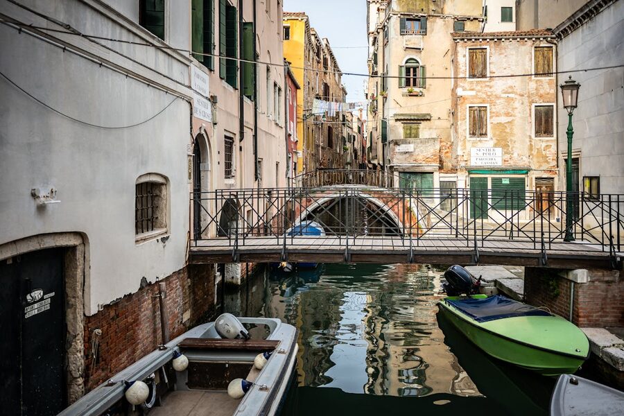 Charming Venice canal scene with boats moored along buildings and a stone bridge