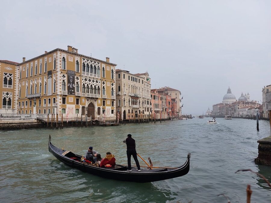 Gondolier steering gondola through narrow Venice canal