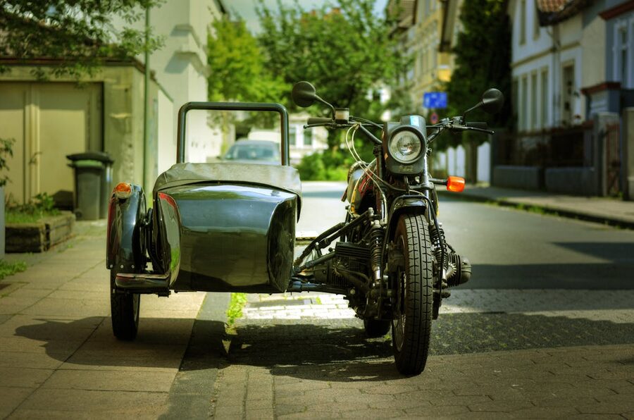 Classic motorcycle with sidecar parked on a city street in sunlight