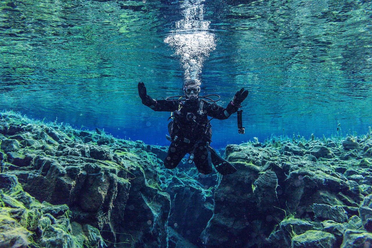 Diver in drysuit exploring the crystal clear waters of Silfra fissure between tectonic plates in Iceland