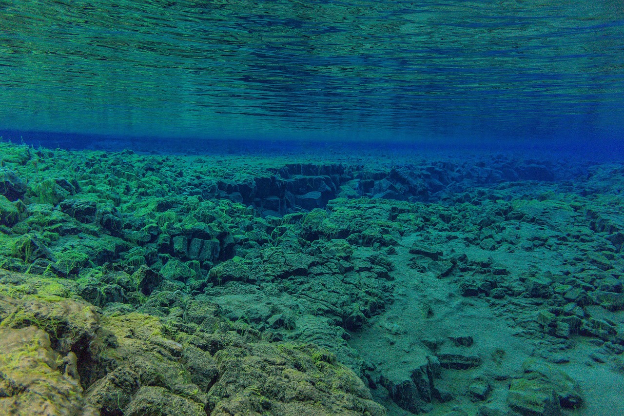 Crystal clear glacial water in Silfra fissure showing underwater rock formations between tectonic plates in Iceland