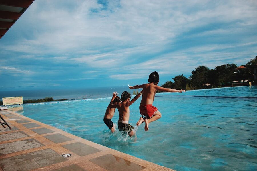 Kids jumping into a pool on a sunny summer day