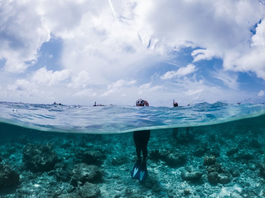 Person in snorkeling gear standing in turquoise seawater