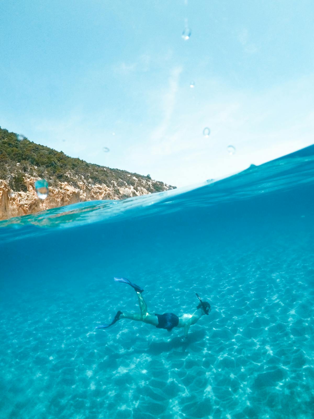 A person snorkeling in the crystal clear blue waters of Sardinia Italy